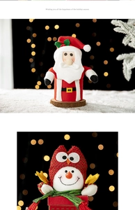 Christmas plush Santa doll and gift box ornament set on white snow with festive lights