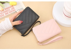 Detail view of chevron quilted faux leather wallets in black and pink with wrist straps