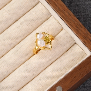 Close-up of vintage gold ring featuring irregular frame, baroque pearls and leaf detail