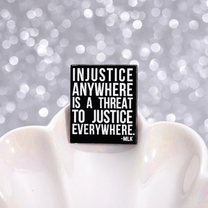 Detail of MLK quote enamel pin on iridescent shell tray with shimmering bokeh backdrop