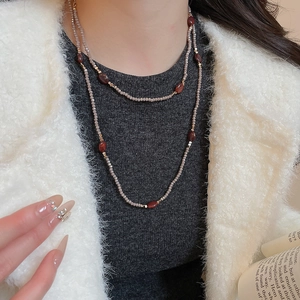 Detail of double-layer beaded necklace featuring tiger eye stones on grey sweater