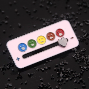 Macro shot of pink enamel mood tracker brooch with sliding silver heart and icons