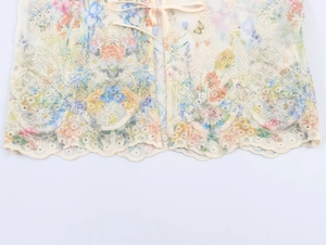 Close-up of beige lace fabric with floral embroidery and wavy scalloped hem detail