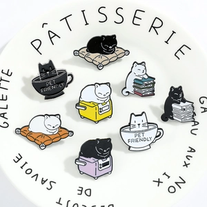 Set of eight assorted enamel cat badges featuring pet friendly text on a white plate