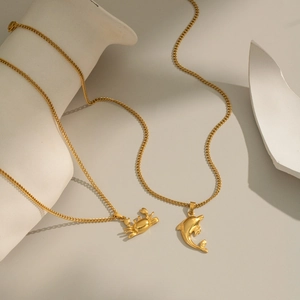 Colliers en acier inoxydable plaqué or 18K avec pendentifs crabe et dauphin sur décor blanc
