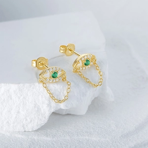 Detailed macro view of S925 silver eye earrings with green stone and golden chain tassels