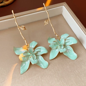 Detail of vintage mint green enamel flower earrings with golden leaves in a jewelry box