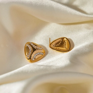 Macro detail of 18k gold plated teardrop earrings with crystals on silk background