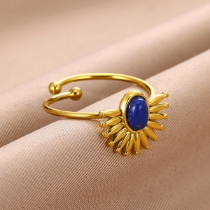 Détail de la bague soleil dorée avec pierre turquoise bleue sur fond en tissu de soie