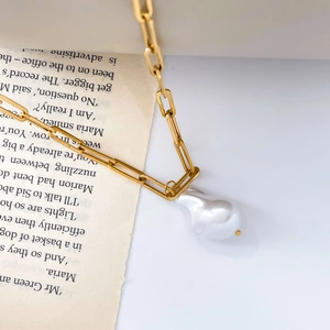 Macro shot of large baroque pearl pendant on gold paperclip link chain necklace