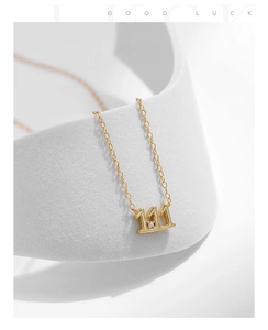 Vue macro du pendentif chiffre chanceux 111 doré avec pierre zircon sur chaîne fine
