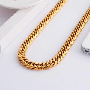 Polished gold-tone titanium Cuban link necklace displayed on a minimalist white tray