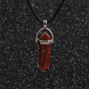 Macro shot of red hexagonal crystal pendant necklace on a black braided cord