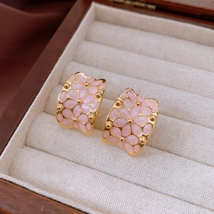 Macro detail of 18k gold plated C-shaped earrings with pink enamel flower pattern