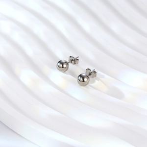 Polished silver titanium steel ball stud earrings on a wavy white background