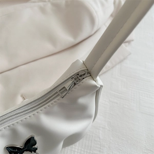 Minimalist white leather underarm bag featuring a stylish black butterfly metal accent