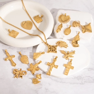 Collection de pendentifs dorés en acier inoxydable avec croix et cœur sur marbre