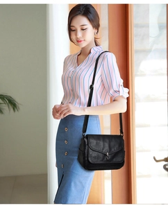 Detail of black soft leather shoulder bag featuring a metallic swivel lock and flap closure