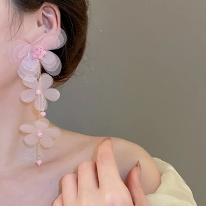 Close-up of pink chiffon flower tassel earrings worn by a model in soft lighting