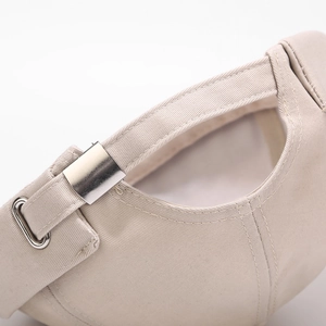 Detail of adjustable cotton strap and silver metal buckle on a beige brimless docker hat