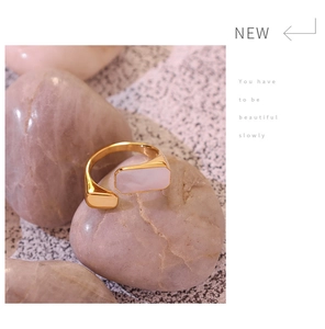 Detail of adjustable gold ring with white rectangle shell stone on smooth white stones
