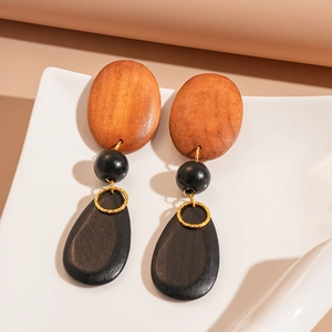 Detailed view of geometric wooden drop earrings with oval and teardrop beads on ceramic