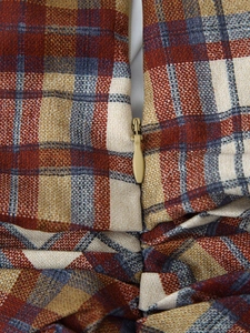Macro detail of plaid fabric with beige teardrop zipper on loose checkered dress