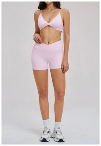 Detail of high-waist criss-cross yoga shorts and cross-neck top in light pink fabric