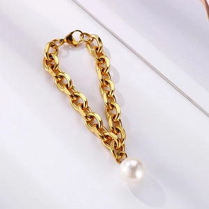 Detail view of gold chunky chain bracelet with white pearl pendant and lobster clasp