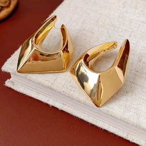 Close-up of gold-plated irregular geometric earrings on a textured linen notebook