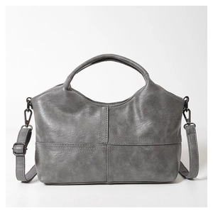 Close-up of grey leather handbag showing stitched texture and metal strap buckles