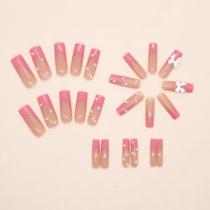 Flat lay of pink gradient press-on nails with 3D bows and pearl accents in a set
