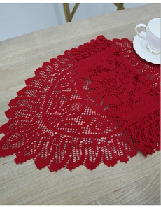 Macro detail of red lace crochet table runner on a light wooden table with white tea cup