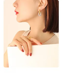 Detail of textured oval earrings and gold ring on model with minimalist modern design