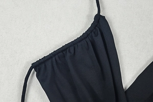 Detail shot of the ruched side seam and delicate thin strap on a black backless dress