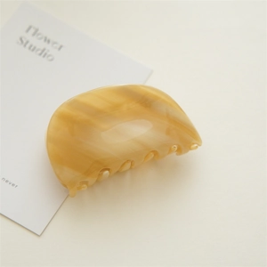 Detail of elegant beige acetate hair claw clip with cream marble texture and smooth finish