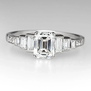 Elegant emerald cut solitaire ring with baguette side stones and pave diamonds set in white gold