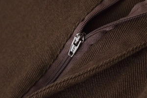 Detaillierte Makroansicht des SBS-Metallreißverschlusses und der braunen Denim-Stoffstruktur