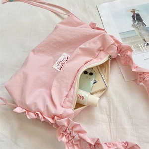 Detailed view of pink pleated nylon shoulder bag with ruffled strap and white fabric label
