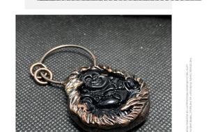 Makroaufnahme von handgeschnitztem Buddha-Anhänger aus schwarzem Kristall mit Bronzeverzierung