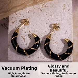 Detail showing C-shaped black earrings with golden spiral texture on stone surface