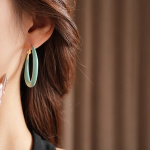 Gros plan d'une boucle d'oreille C en résine bleu clair avec fermoir doré sur un mannequin
