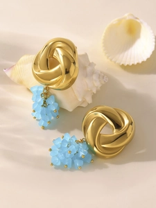 Detail of gold geometric earrings with light blue faceted glass beads on seashell