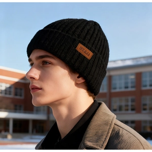 Close-up of black ribbed knit beanie with brown leather logo patch on male model