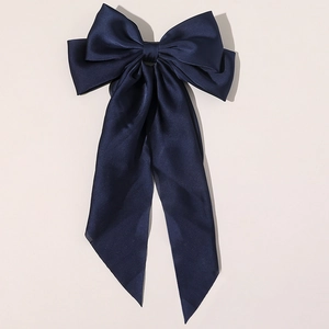 Close-up of the smooth dark blue satin fabric and large bow design on the hair clip