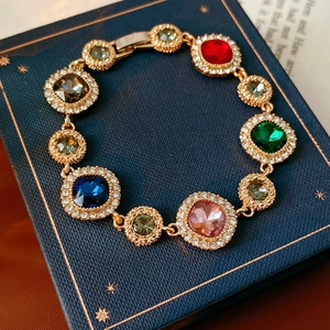 Detail of vintage gold bracelet featuring colorful gems and sparkling crystal halo