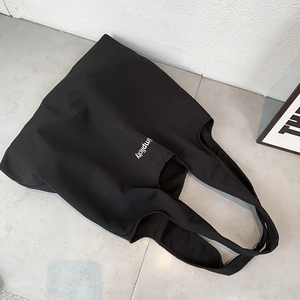 Vue détaillée du sac cabas en toile noire avec texte Simplicity blanc imprimé à l'avant