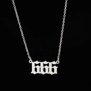 Macro shot of silver stainless steel necklace with gothic 666 number pendant on black background