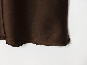 Detail view of deep brown satin midi skirt hem showing silk texture and fine stitching