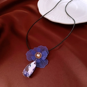 Détail de fleur en métal bleu et pendentif en cristal violet sur cordon noir